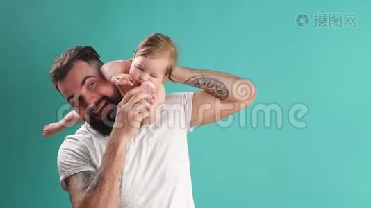 嬉戏的父亲带着他微笑的婴儿在蓝色背景的脖子上视频