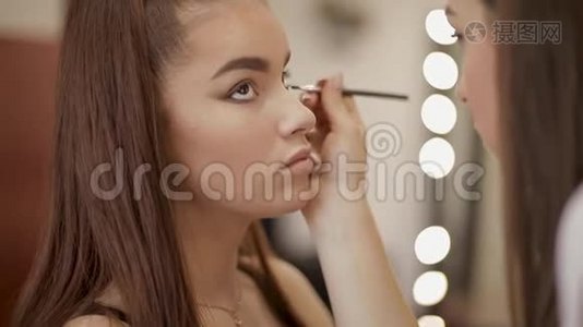化妆师用雀斑的年轻红发女人做职业化妆视频