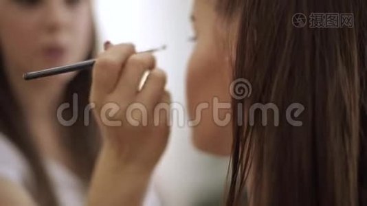 化妆师用雀斑的年轻红发女人做职业化妆视频