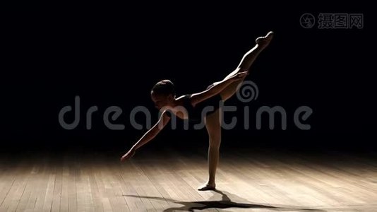 年轻的少女在黑暗中缓慢地在舞台上跳芭蕾。视频