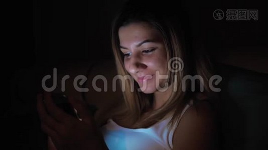 在睡觉前使用智能手机的黑暗中的女人，脸从屏幕上发光视频