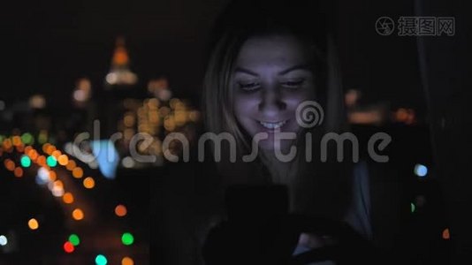 站在窗口的黑暗中的女人使用从屏幕4k照亮的移动脸视频