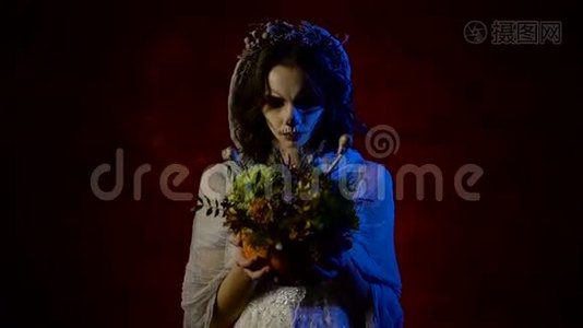 一个年轻新娘的鬼魂正站在她手里拿着一束花。 有艺术头骨的神秘女人视频