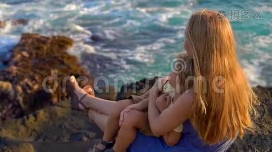 一对母亲和儿子坐在岩石上看着塔纳罗得寺附近的海浪慢镜头视频