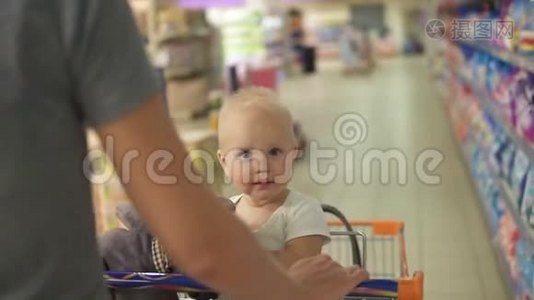 小宝宝坐在超市里的一辆购物车里，手里拿着一个玩具，而她的妈妈正在推着手推车走在中间视频