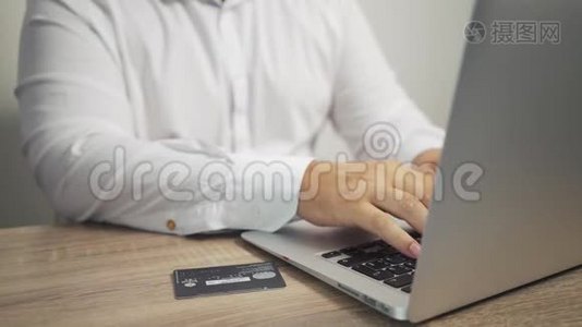 网上购物概念。 男人手拿信用卡，用笔记本电脑。 信用卡在桌子上视频
