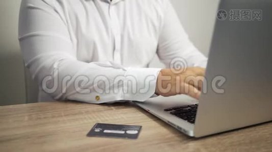 网上购物概念。 男人手拿信用卡，用笔记本电脑。 信用卡在桌子上视频