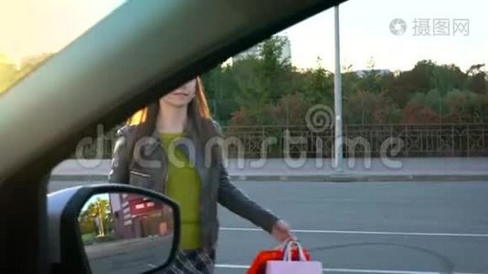 女人把购物袋放在汽车座椅上，坐在其中，打算开车离开。视频