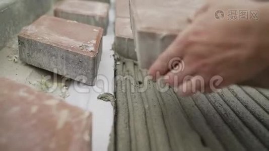 工人把胶水涂在路面上的瓷砖上。视频