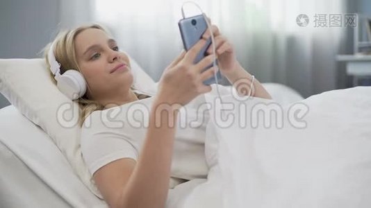 戴耳机的青少年在床上听音乐，在社交媒体上交流视频
