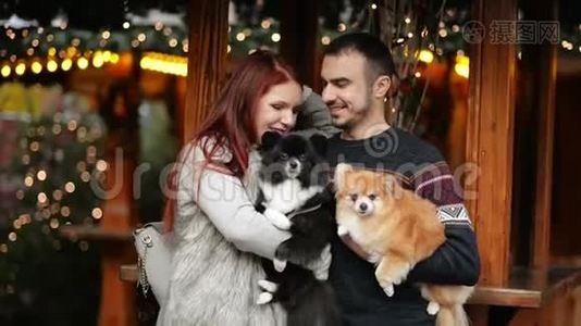 年轻夫妇在圣诞节的时候在户外玩。 他们抱着可爱的狗。 新年快乐概念。视频