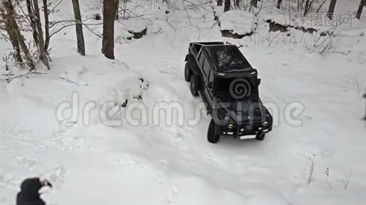 越野车要从深坑里骑出来，在白雪覆盖的道路上冬天的森林。 非公路视频