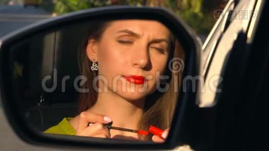 女人用红色口红涂嘴唇，看着后视镜视频