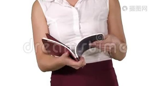女人手拿着笔记本，翻页看着白色背景。视频