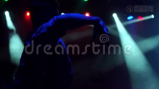 一个年轻人在黑暗中用聚光灯跳舞。视频