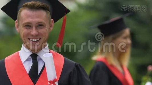 男毕业生，穿着大学文凭，微笑着拍照视频