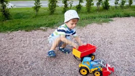 可爱的幼儿男孩在公园里玩玩具装载机和拖车的4K镜头视频