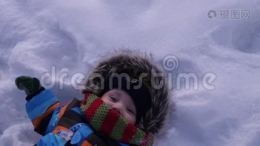 那孩子躺在雪地里。 做雪天使视频