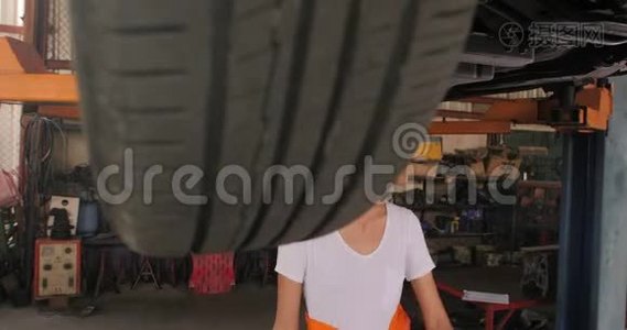 年轻漂亮的汽车修理工在车库里检查汽车底盘。视频