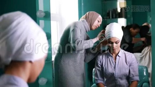 靠近镜子的穆斯林妇女将伊斯兰头巾系在漂亮的新娘身上视频