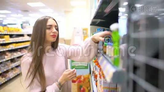 年轻的女人在超市里选择婴儿食品，母亲在市场上为孩子选择食物，女孩站在附近视频