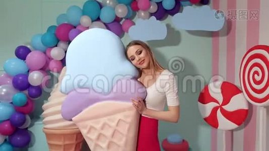 一个可爱的女孩拿着一个巨大的冰淇淋在工作室的背景上巨大的糖果视频