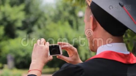 穿着学术服装的人在手机上拍照，毕业日视频