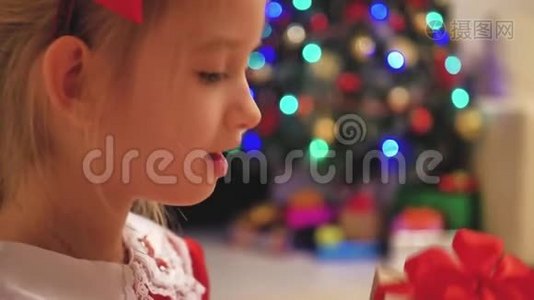 穿着红色裙子的女孩打开圣诞礼物。 带着圣诞礼物盒的快乐微笑的小女孩。 舒适温暖视频