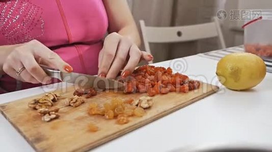 一位年轻的家庭主妇用一把刀在砧板上切果干杏子. 健康饮食观念视频