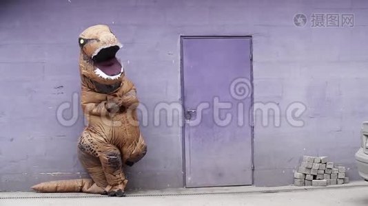 穿着雷克斯吉祥物服装的男人站在紫色墙上的门旁视频