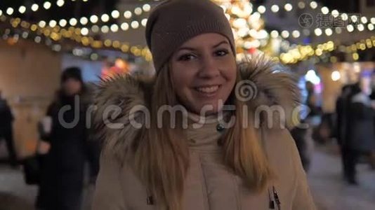 穿着温暖衣服微笑的女人，站在圣诞市场上照明视频
