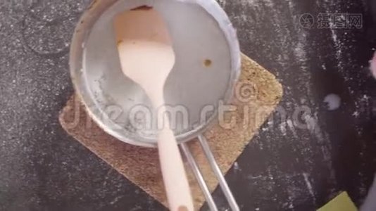 一只糖果手把融化的糖和牛奶混合在锅里视频