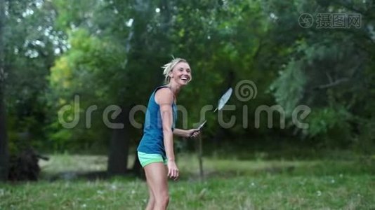 漂亮的微笑，运动健身女人在公园打羽毛球。视频