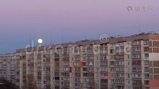 一栋多层建筑屋顶上方的满月正在上升视频