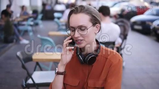 智能手机女人坐在咖啡馆里打电话。 她在笑。 漂亮的年轻女性休闲装视频