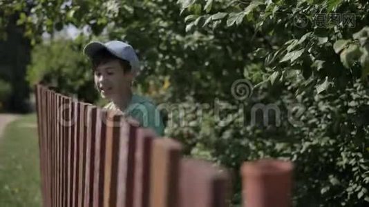 一个带弹弓的滑稽男孩瞄准了村里一个靠近栅栏的人视频