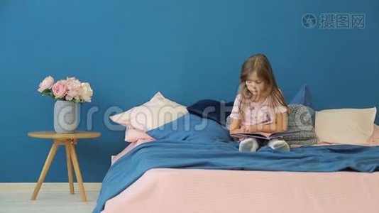 一个小女孩正在床上看书。视频
