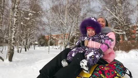 快乐的妈妈和女儿在冬天的雪中雪橇，玩雪球。 母亲和孩子笑着快乐地在视频