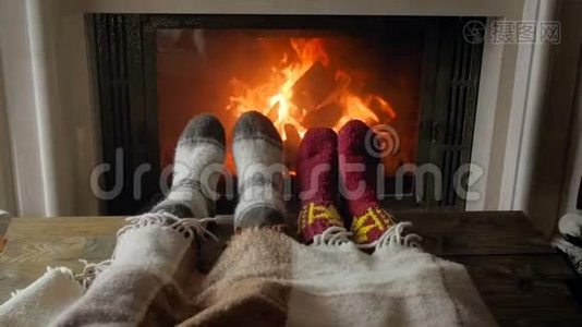 一对徜徉的情侣躺在毯子下，晚上用燃烧的壁炉温暖双脚视频