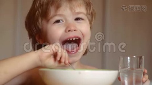 饥饿的小男孩在吃东西。 童年。 孩子在家吃健康的食物。 微笑快乐可爱宝宝吃水果泥视频