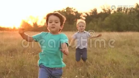 日落时，两个小男孩跑过田野。视频