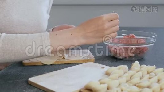 女人用肉馅包饺子，特写的手。 侧视。视频