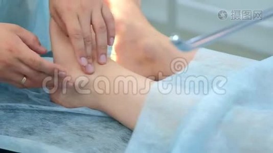 外科医生在手术前触诊腿部，以去除关节中的脚踝湿瘤，特写。视频