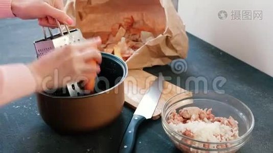 特写的女人`她的手在平底锅里的烤炉上搓胡萝卜。视频