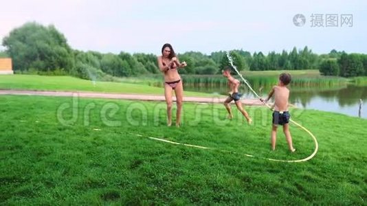 这两个男孩正和爸爸妈妈在他们家的后院玩耍，他们的房子里充满了水，笑着笑着。视频