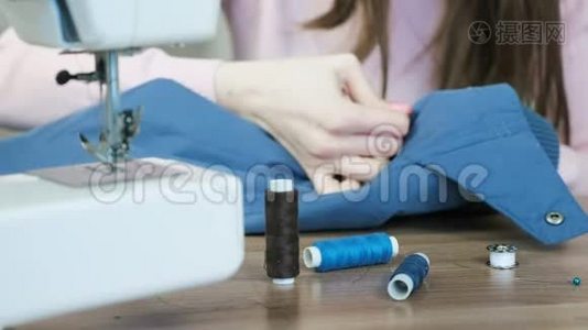 贴身女人`用缝纫机用手把皮革插入到蓝色夹克上。视频