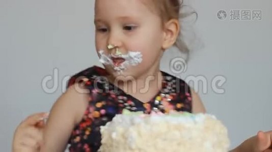 生日快乐。 一个可爱的小女孩吃一个脏脸和脏手的蛋糕。 一个在餐桌上吃甜点的孩子。 特写视频