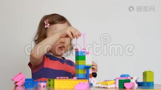 小女孩玩五颜六色的小积木的一个建设者。 孩子培养自己的思维能力.. 发展视频