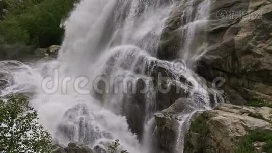 慢动作的水从一块巨大的岩石上掉下来。 阴天有小雨的自然环境中的瀑布视频