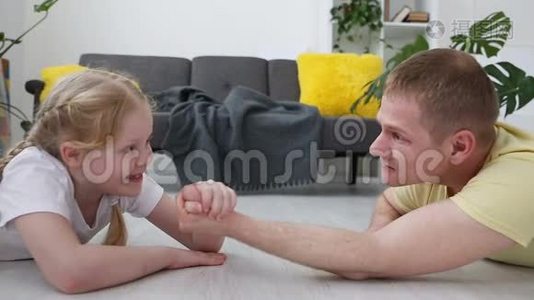 快乐的现代家庭。 爸爸和他的小女儿是用客厅地板上的力来衡量的。视频